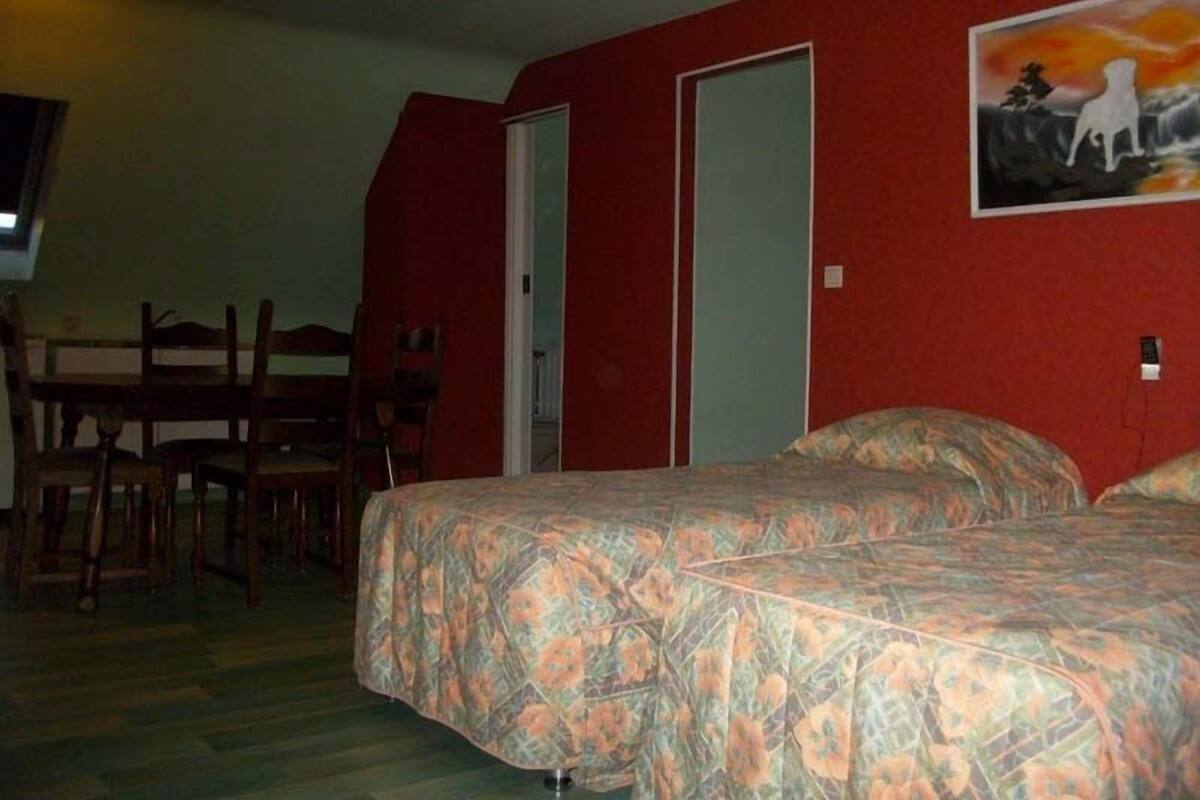 Une chambre avec deux lits, une table à manger avec des chaises et un tableau au mur.