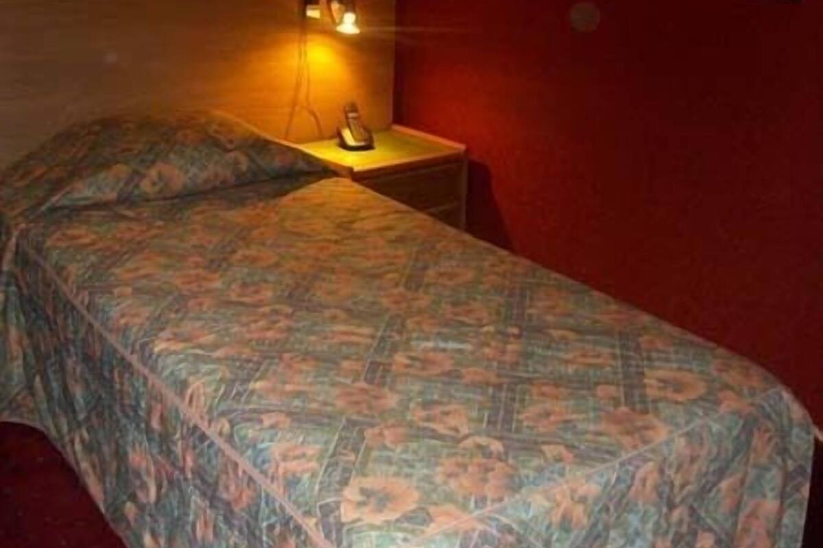 Un lit simple avec une couvre-lit à motifs dans une pièce aux murs rouges.