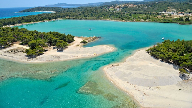 Luftaufnahme einer Küstenregion mit klarem türkisblauem Wasser, Sandstränden und dichten grünen Wäldern.