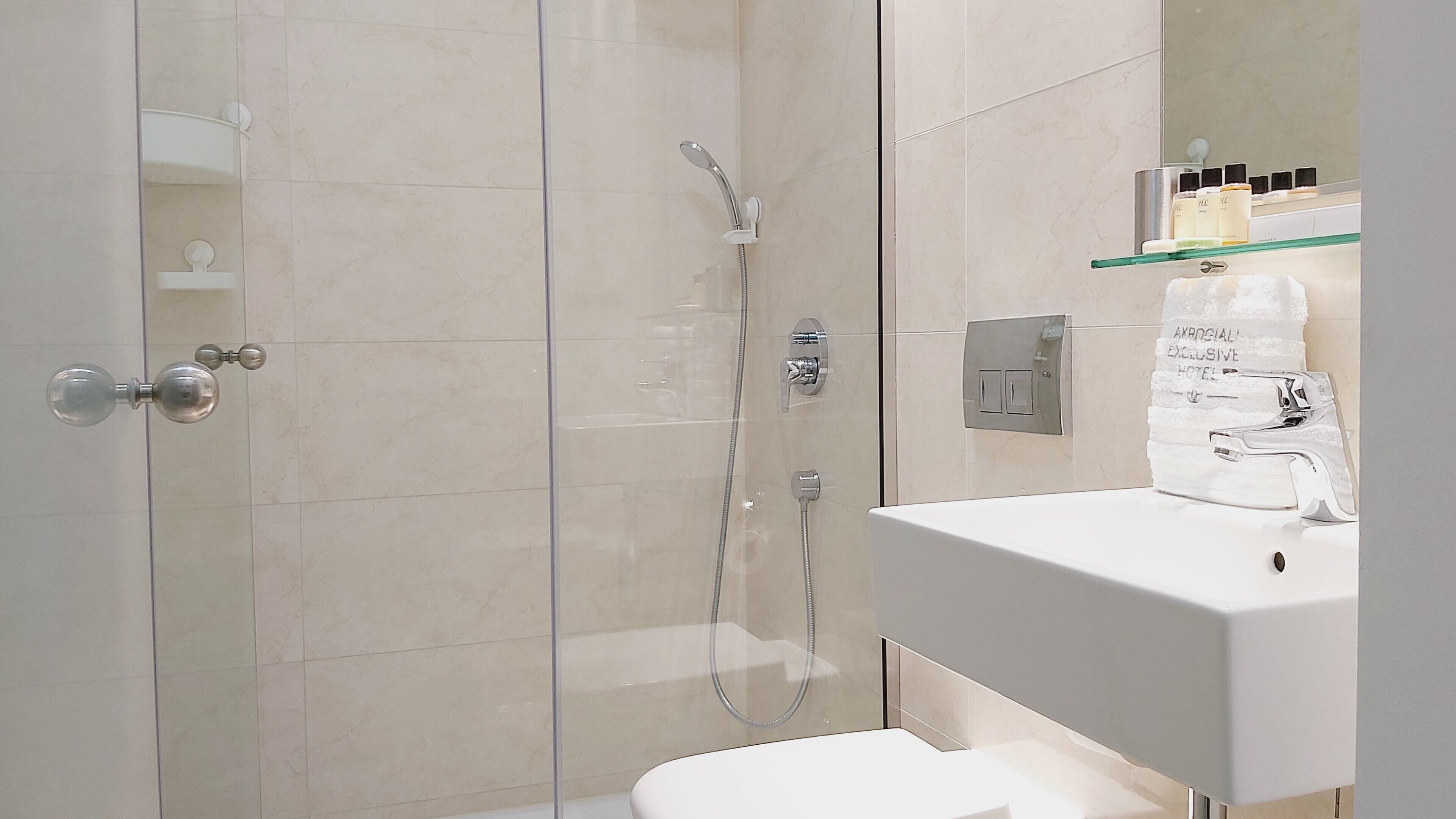Un baño moderno con ducha de vidrio, lavabo blanco y espejo sobre él.