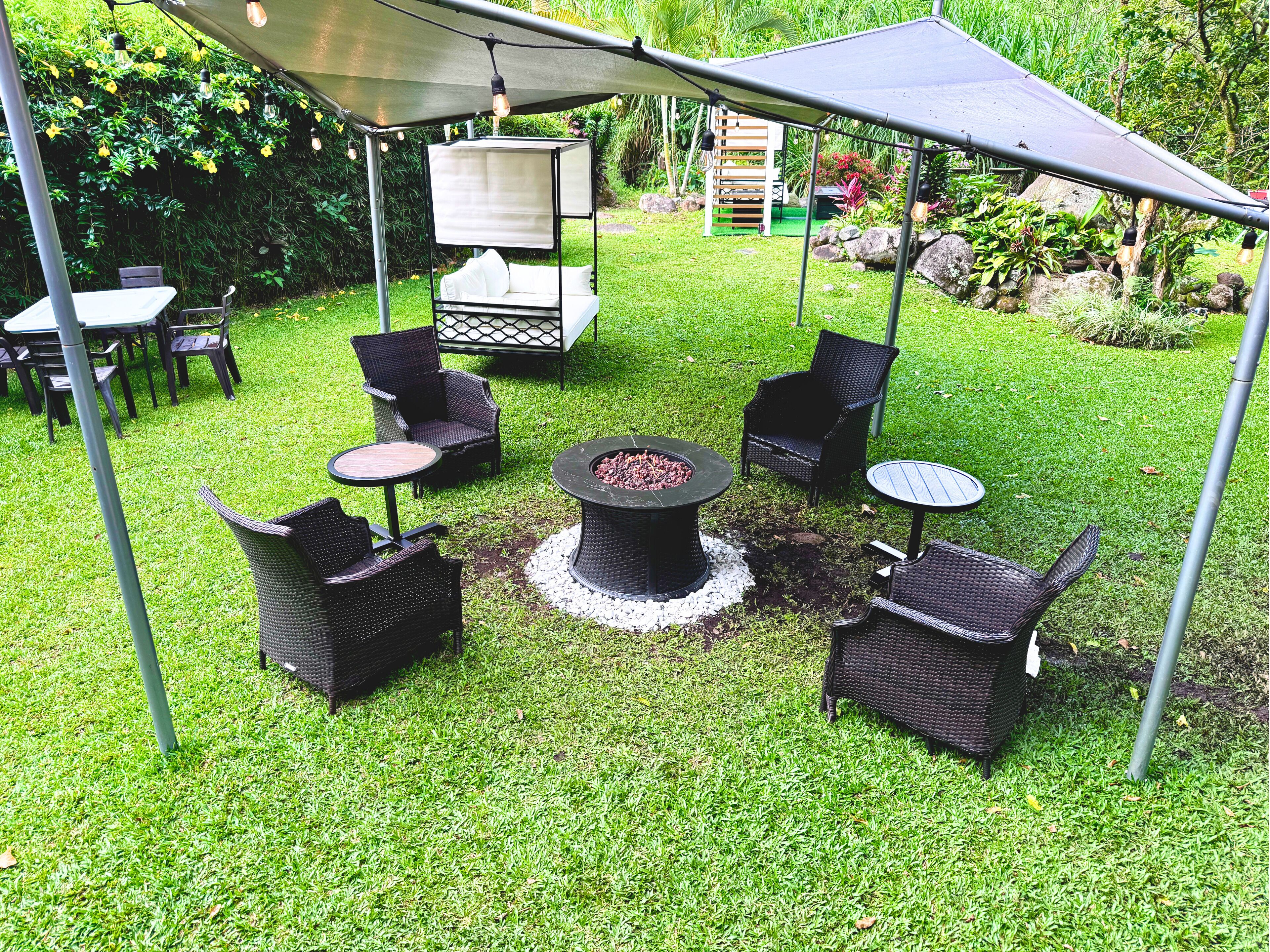 Un espace extérieur aménagé en terrasse, avec des meubles en osier, un foyer et un coin salon abrité.