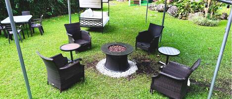 Un espace extérieur aménagé en terrasse, avec des meubles en osier, un foyer et un coin salon abrité.