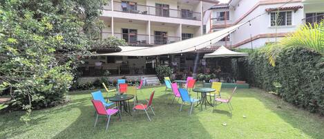 A courtyard with outdoor seating, a covered area, and a multi-story building with balconies.