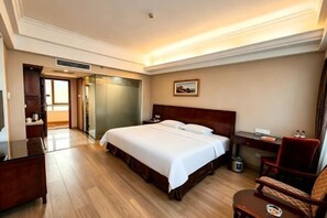 Une chambre d’hôtel avec un grand lit, un bureau, une chaise, une table de chevet et une vue sur l’extérieur.