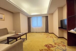 A hotel room with a sofa, a small table, a TV on a stand, and a large window with curtains. - Vienna Hotel (Shenzhen Bijiashan Yinhu subway station) (Shenzhen)