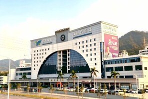 A multi-story building with a large arched entrance, multiple floors, and a parking area in front. - Vienna Hotel (Shenzhen Bijiashan Yinhu subway station) (Shenzhen)