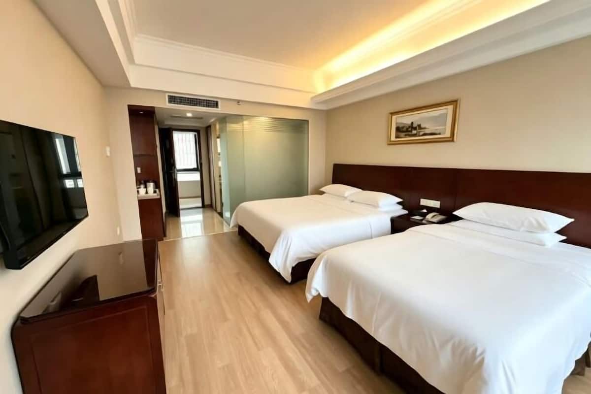 A hotel room with two beds, a TV, and a painting on the wall.