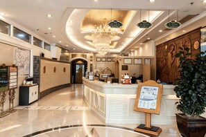 A hotel lobby with a reception desk, a chandelier, and a large potted plant. - Vienna Hotel (Shenzhen Bijiashan Yinhu subway station) (Shenzhen)