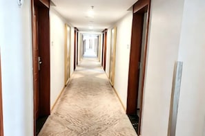 A hotel hallway with carpeted floors, wooden doors, and a long corridor. - Vienna Hotel (Shenzhen Bijiashan Yinhu subway station) (Shenzhen)