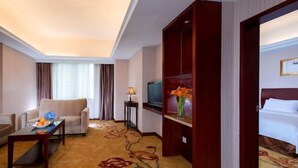A hotel room with a sofa, a small table with fruit, a TV, a bed, and a decorative vase. - Vienna Hotel (Shenzhen Bijiashan Yinhu subway station) (Shenzhen)