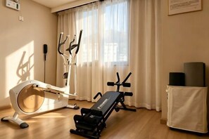 Una habitación con una máquina de ejercicio, una esterilla de yoga y un espacio cubierto.