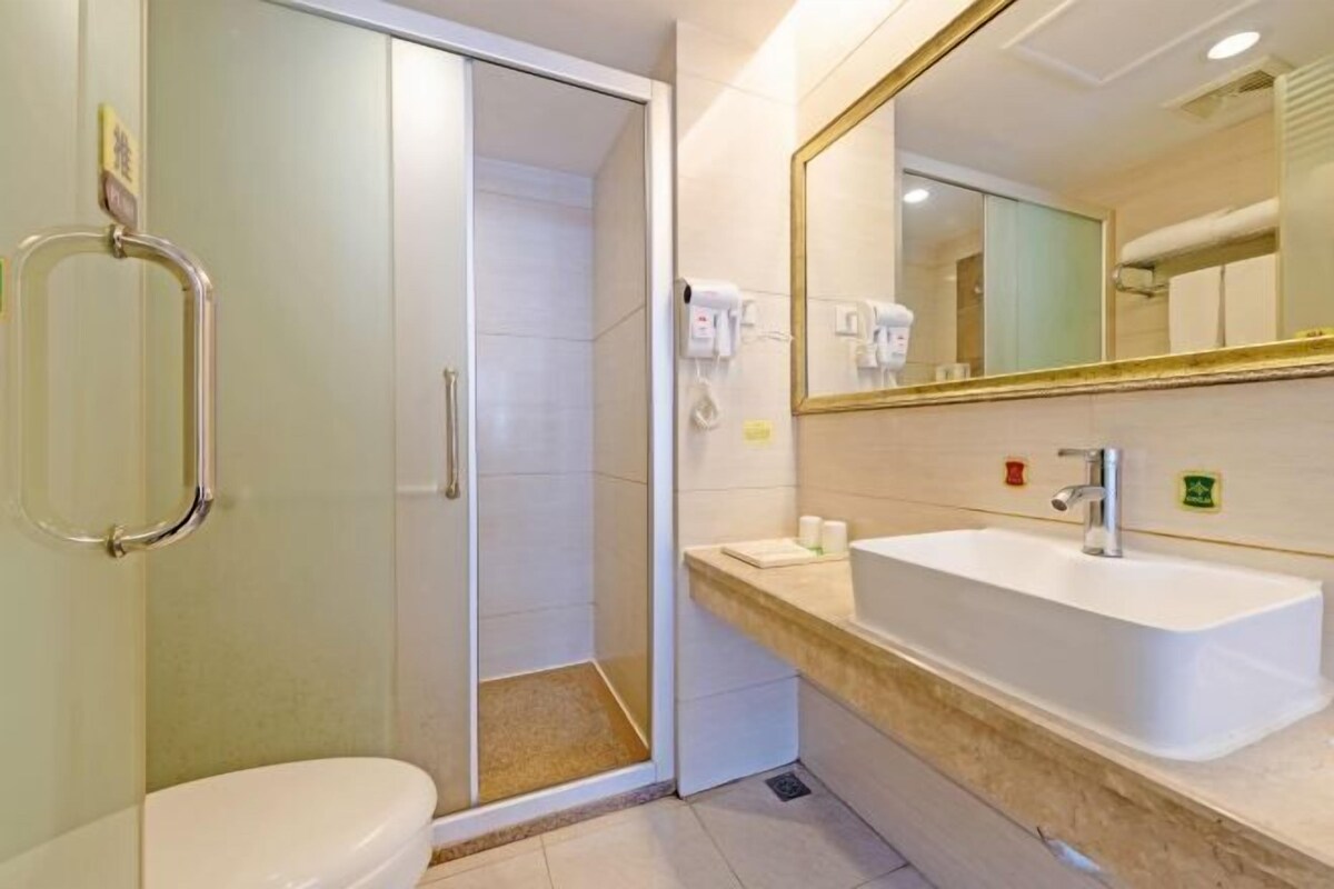 A modern bathroom with a glass shower enclosure, a white sink, and a large mirror.