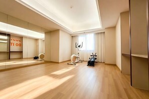 Une pièce spacieuse avec un grand miroir, du matériel d’exercice et une porte coulissante.