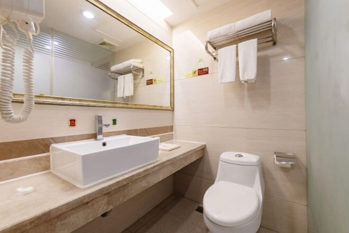 A modern bathroom with a white sink, a large mirror, and a toilet.