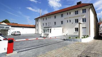 Ein Hotel mit weißer Fassade und rotem Dach, einem verschlossenen Eingang und einem geparkten Auto davor.
