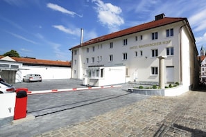A hotel with a white facade and red roof, a gated entrance, and a car parked in front. - Bayerischer Hof Freising (Freising)