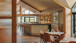A modern restaurant with a bar area, high ceilings, and large windows. - Fairmont Cheshire The Mere (Knutsford)