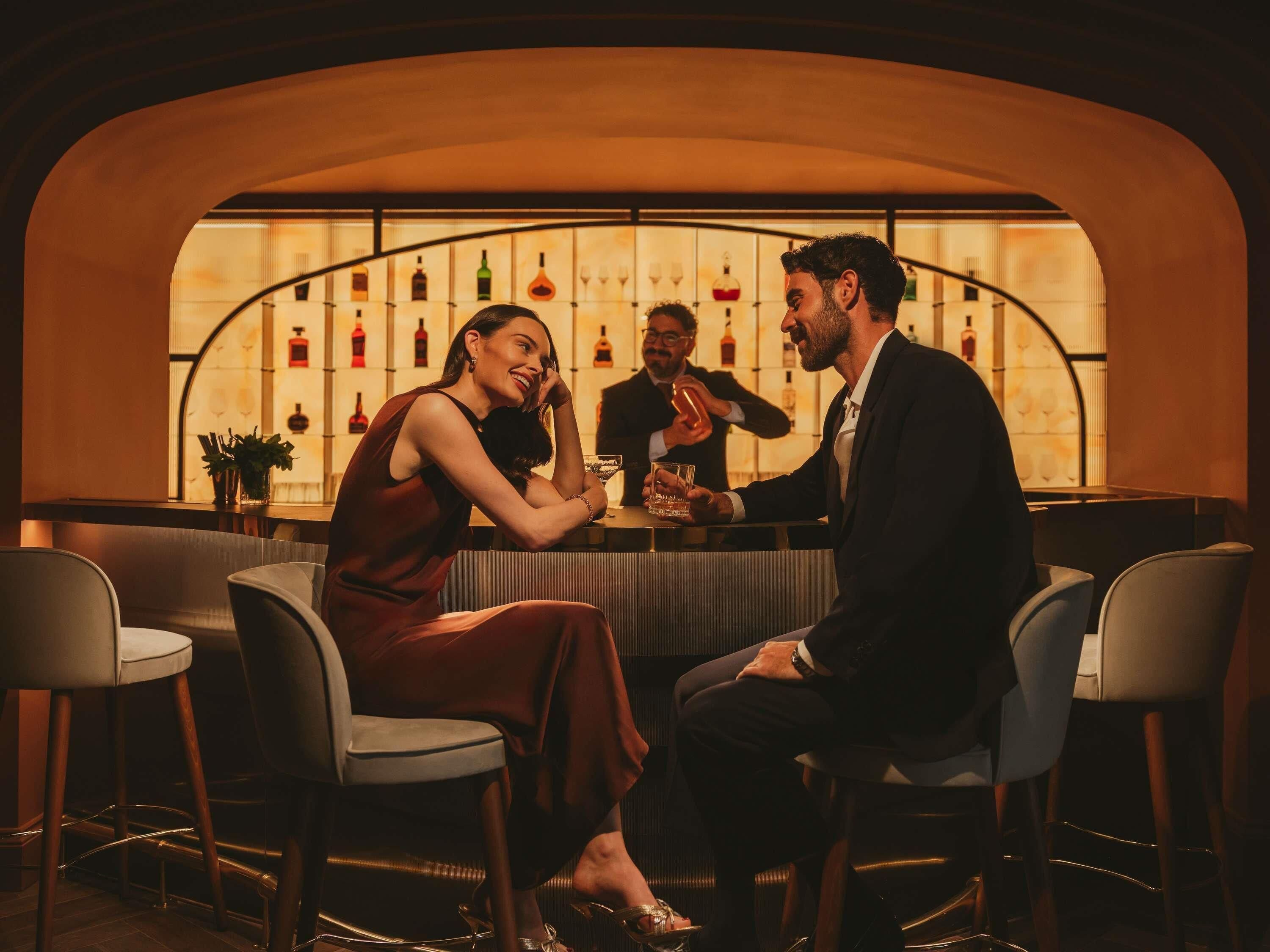 A bar area with a curved wall, bar stools, and a bartender.