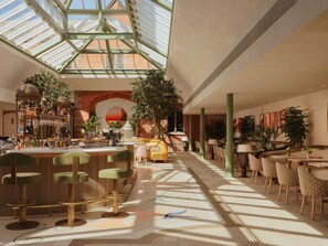 A spacious indoor area with a bar, seating, and a large skylight. - Fairmont Cheshire The Mere (Knutsford)