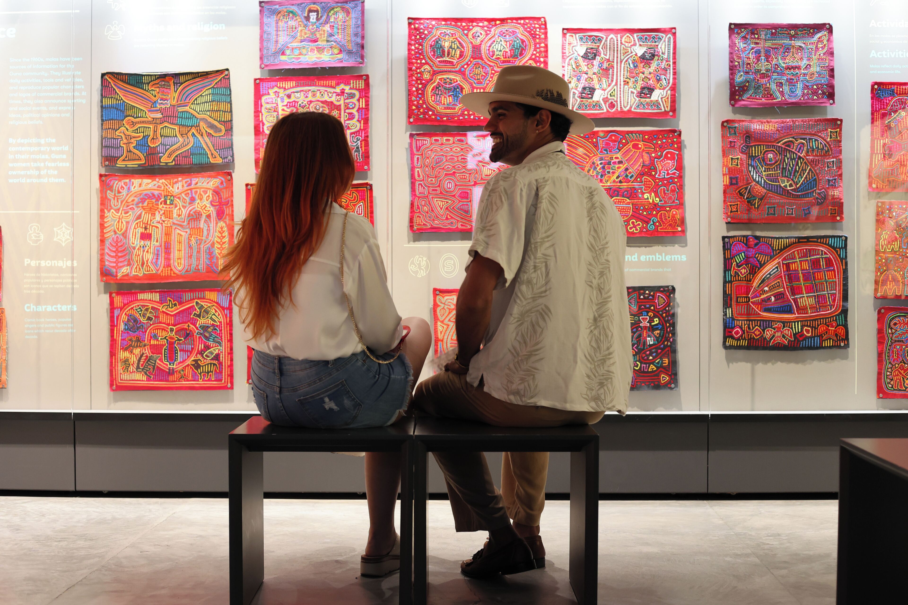 Two people seated at a table in an art gallery with colorful artwork on the walls.