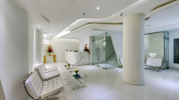 Eine moderne Lobby mit einer Rezeption, einer Sitzecke und Glastüren zu einer Treppe.