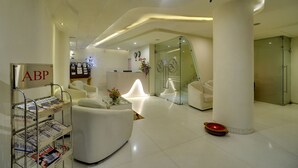 Eine moderne Hotelhalle mit einer Rezeption, weißen Sofas, einem Zeitschriftenständer und einem Duschbereich mit Glaswänden.