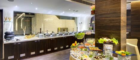 A buffet setup with various food items and a large mirror.