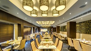Ein geräumiges Restaurant mit mehreren Tischen und Stühlen, eleganten Kronleuchtern und einem modernen Ambiente.