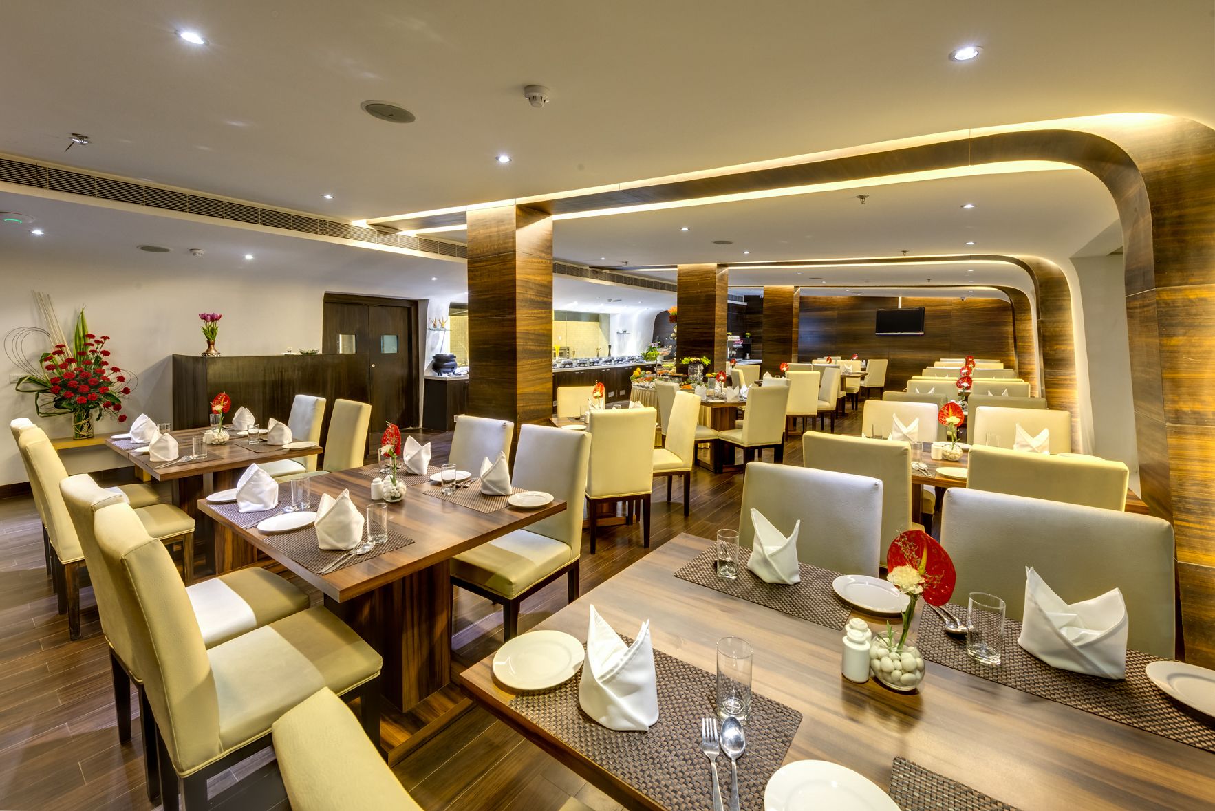 Un restaurante moderno con varias zonas de comedor, incluyendo un salón central y varias mesas más pequeñas.