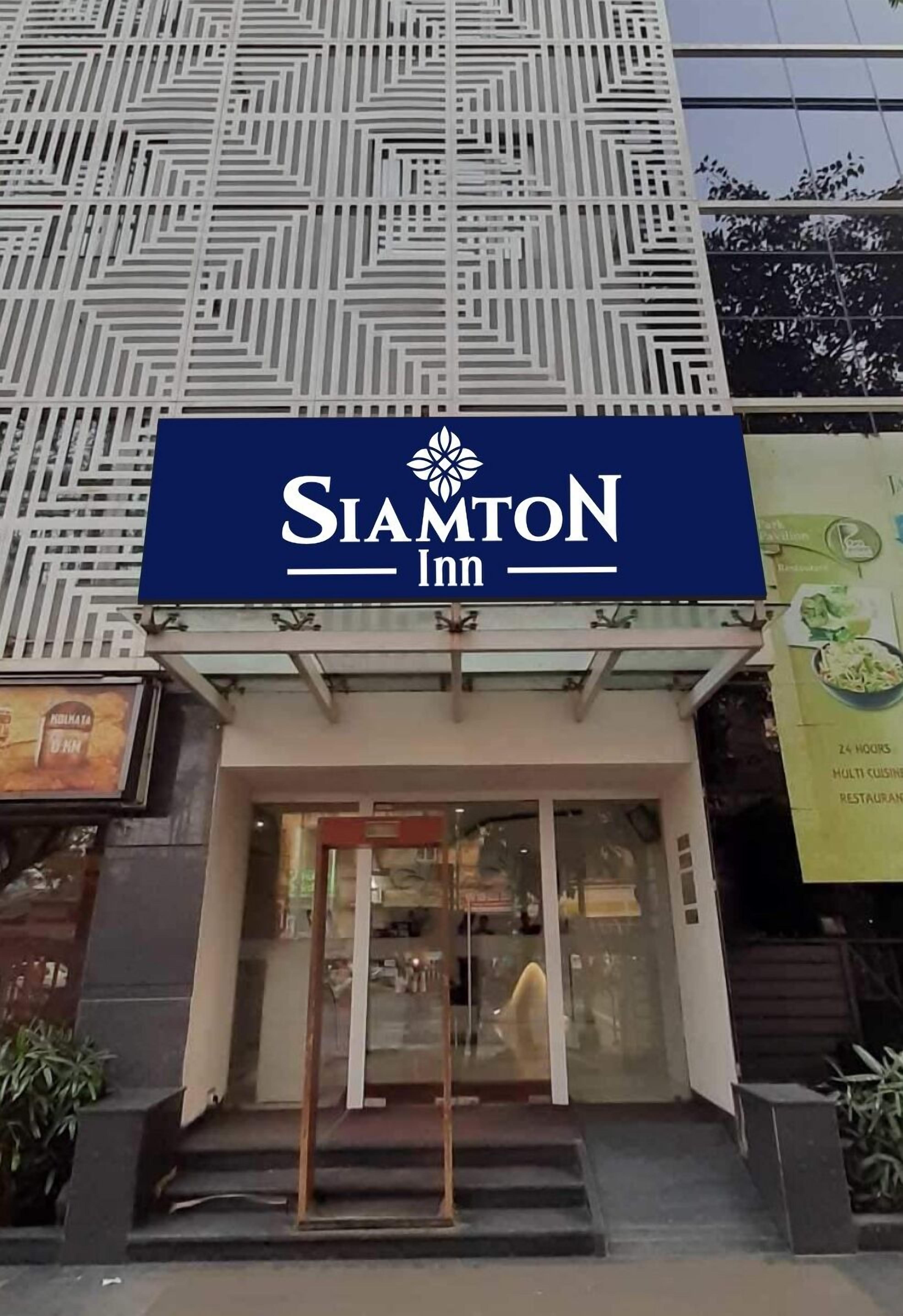 The exterior of SiamtoN Inn, featuring a modern facade with geometric patterns and a prominent entrance with glass doors.