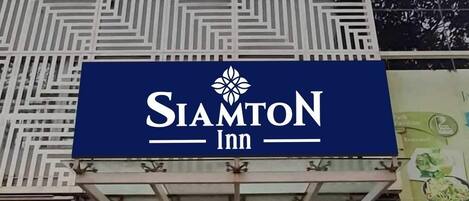 Exterior del SiamtoN Inn, con una fachada moderna que presenta patrones geométricos y una entrada destacada con puertas de vidrio.