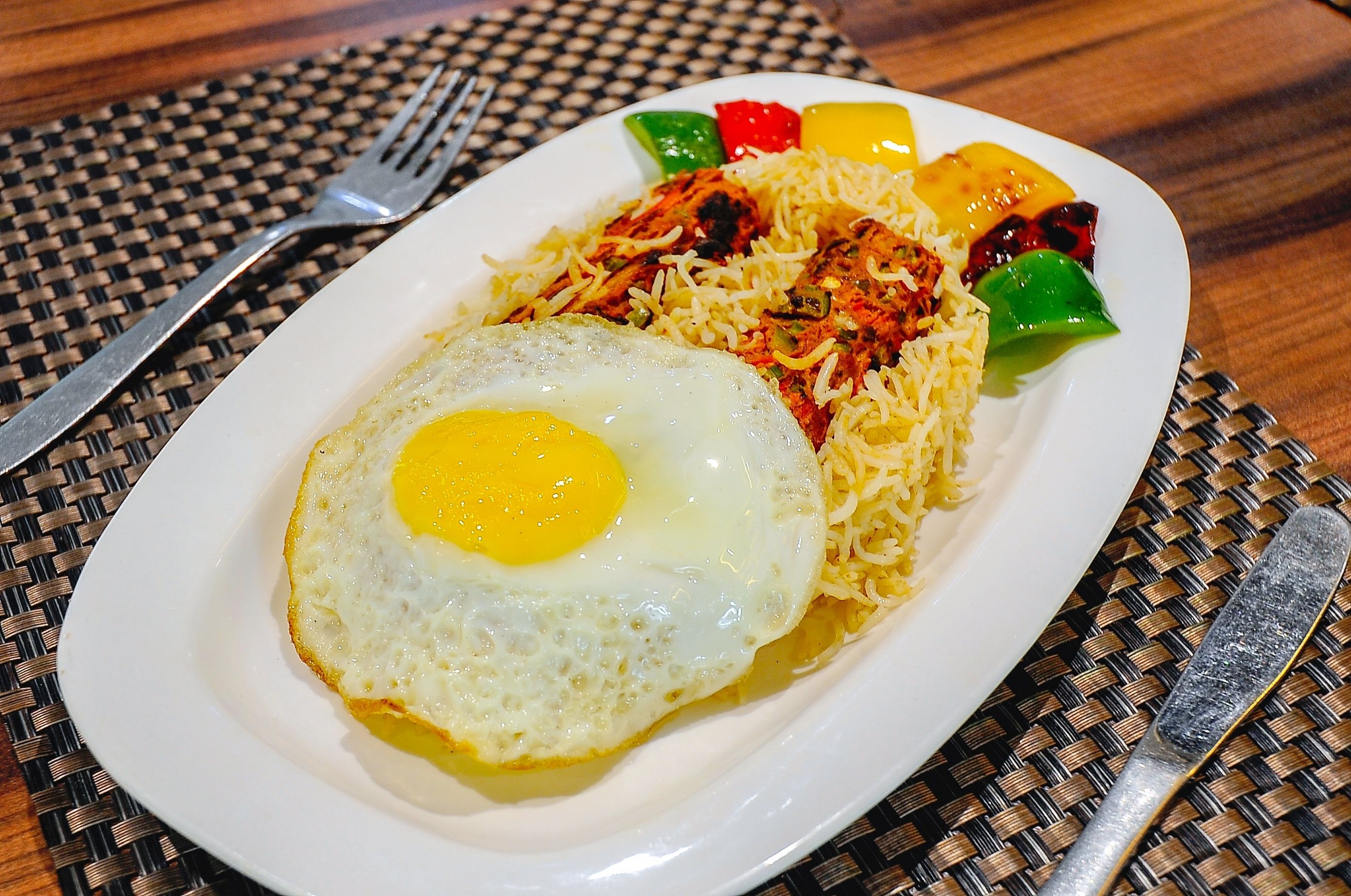 A plate with a fried egg, rice, and grilled vegetables.