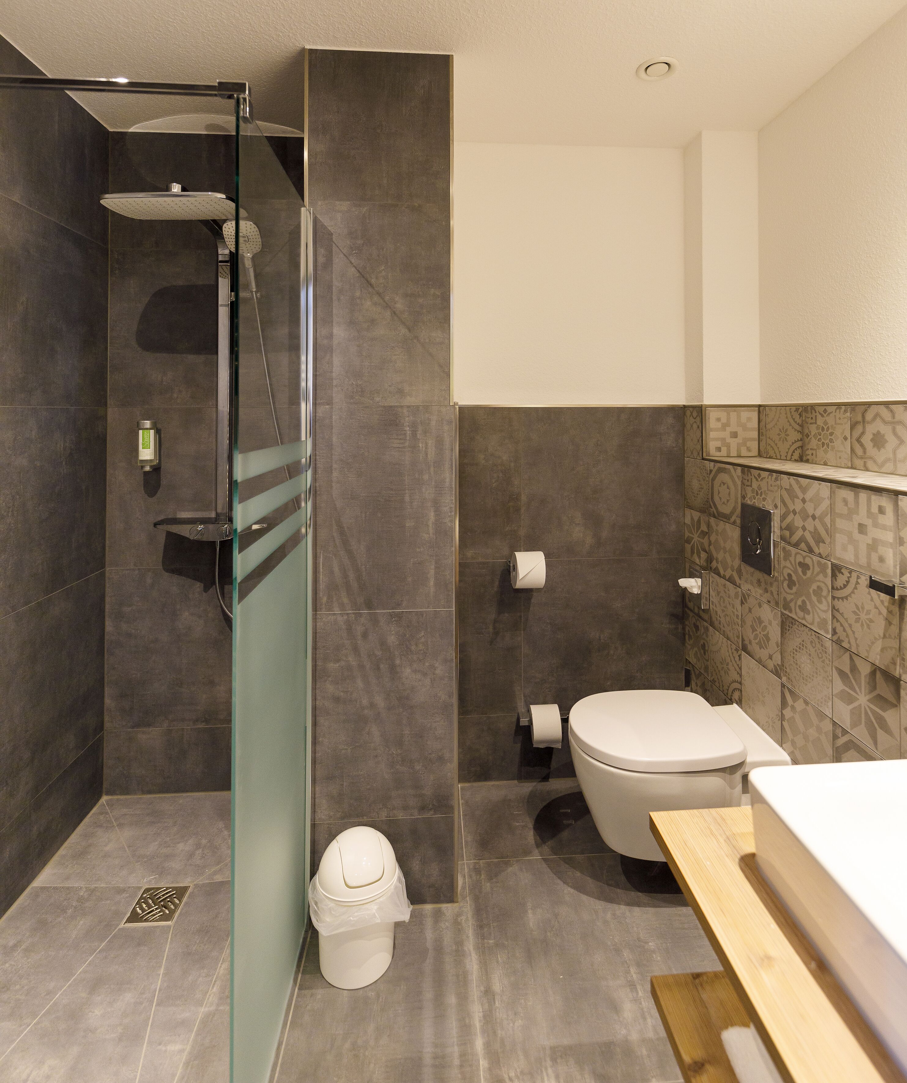 A modern bathroom with a glass-enclosed shower, a toilet, and a sink.