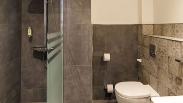 A modern bathroom with a glass-enclosed shower, a toilet, and a sink.
