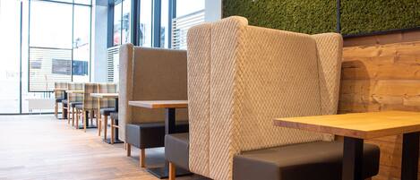 Un café moderne avec un plancher en bois, des sièges confortables et de grandes fenêtres.