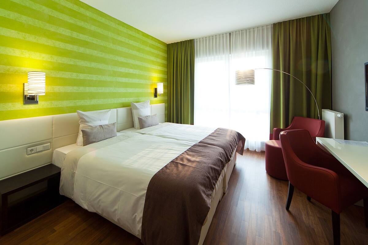 Quarto de hotel com uma cama grande, uma escrivaninha, uma cadeira e uma televisão.