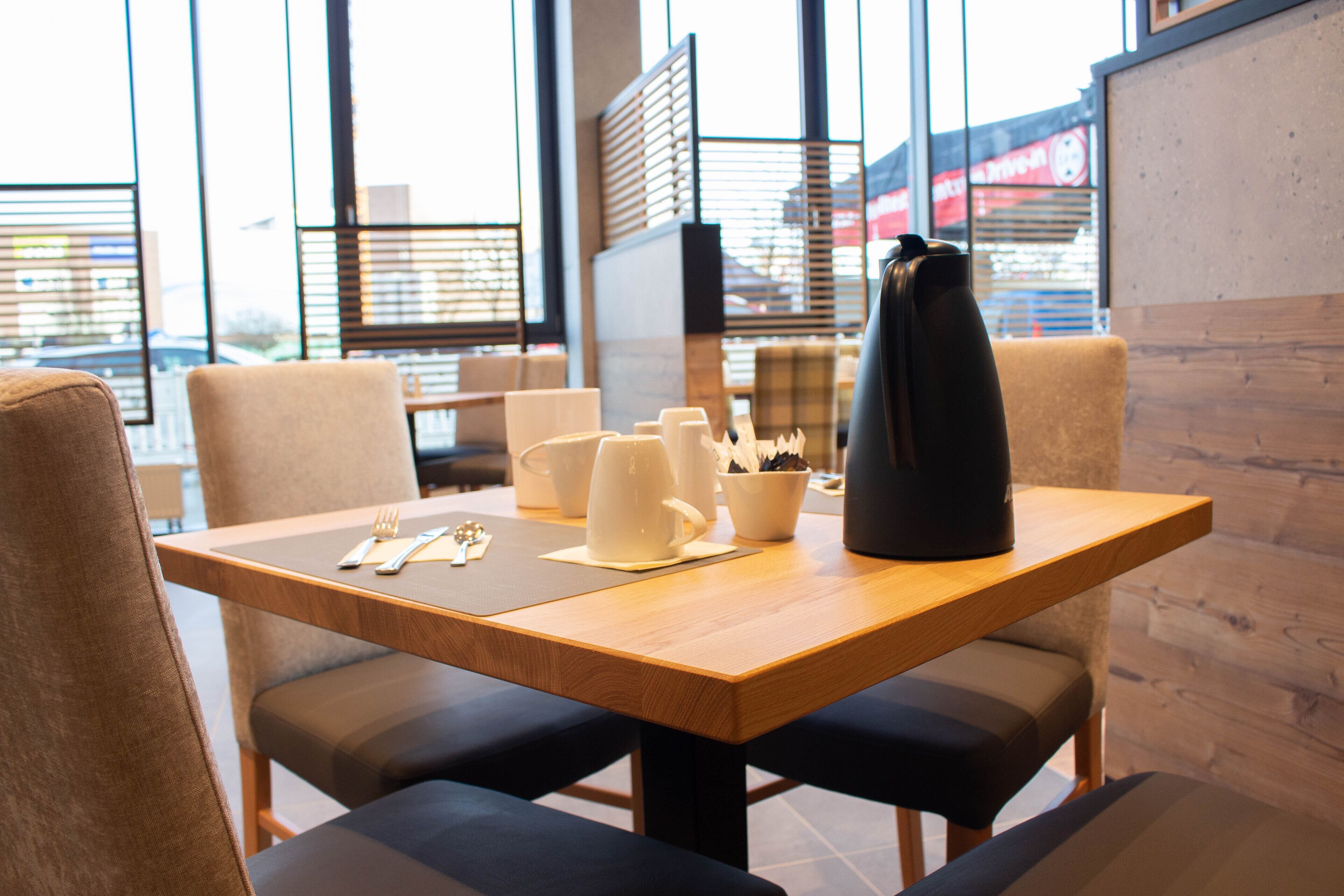 A dining area with a wooden table, four chairs, and a black coffee maker.