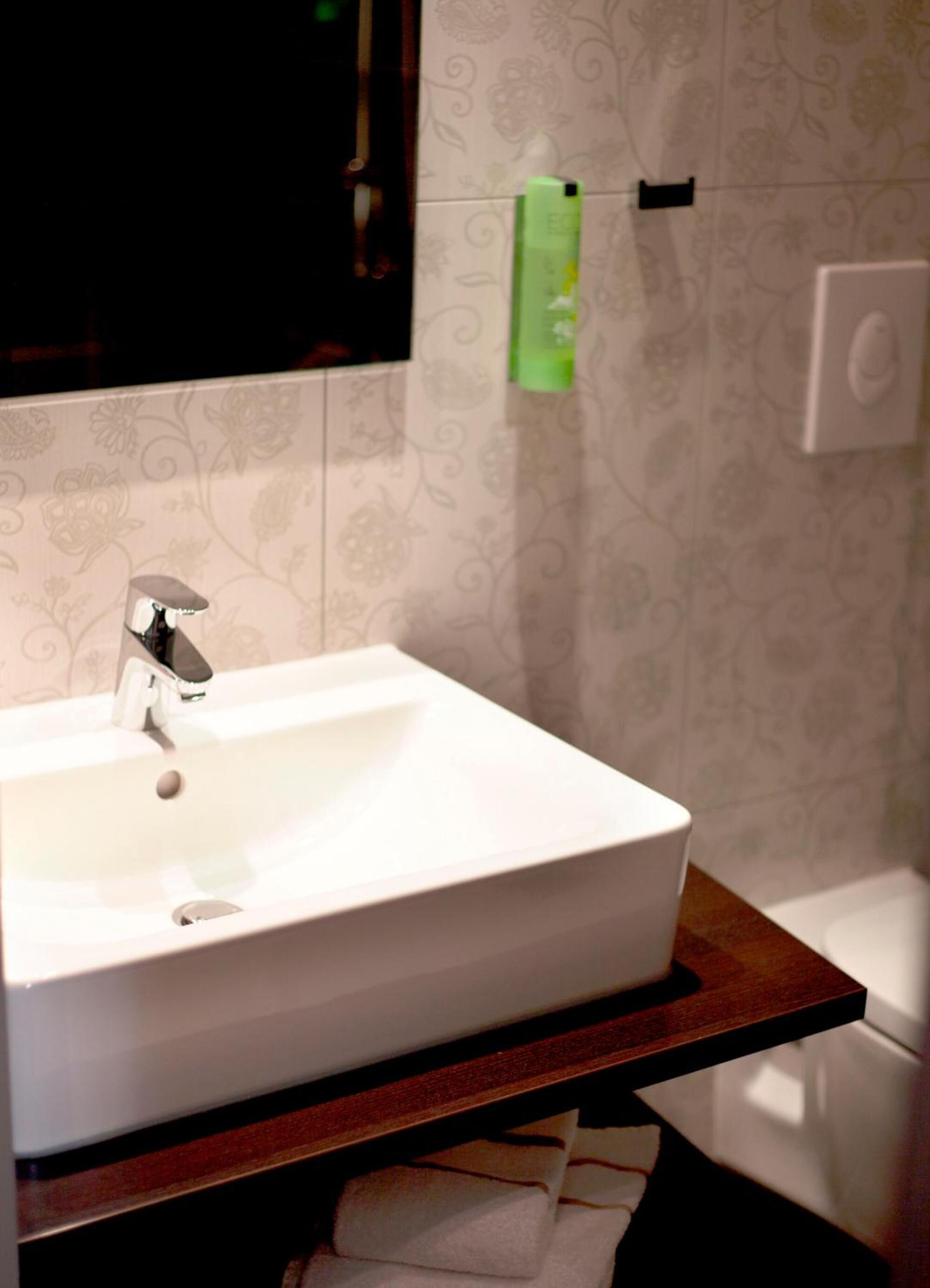 A bathroom with a white sink, a mirror, and a towel rack.