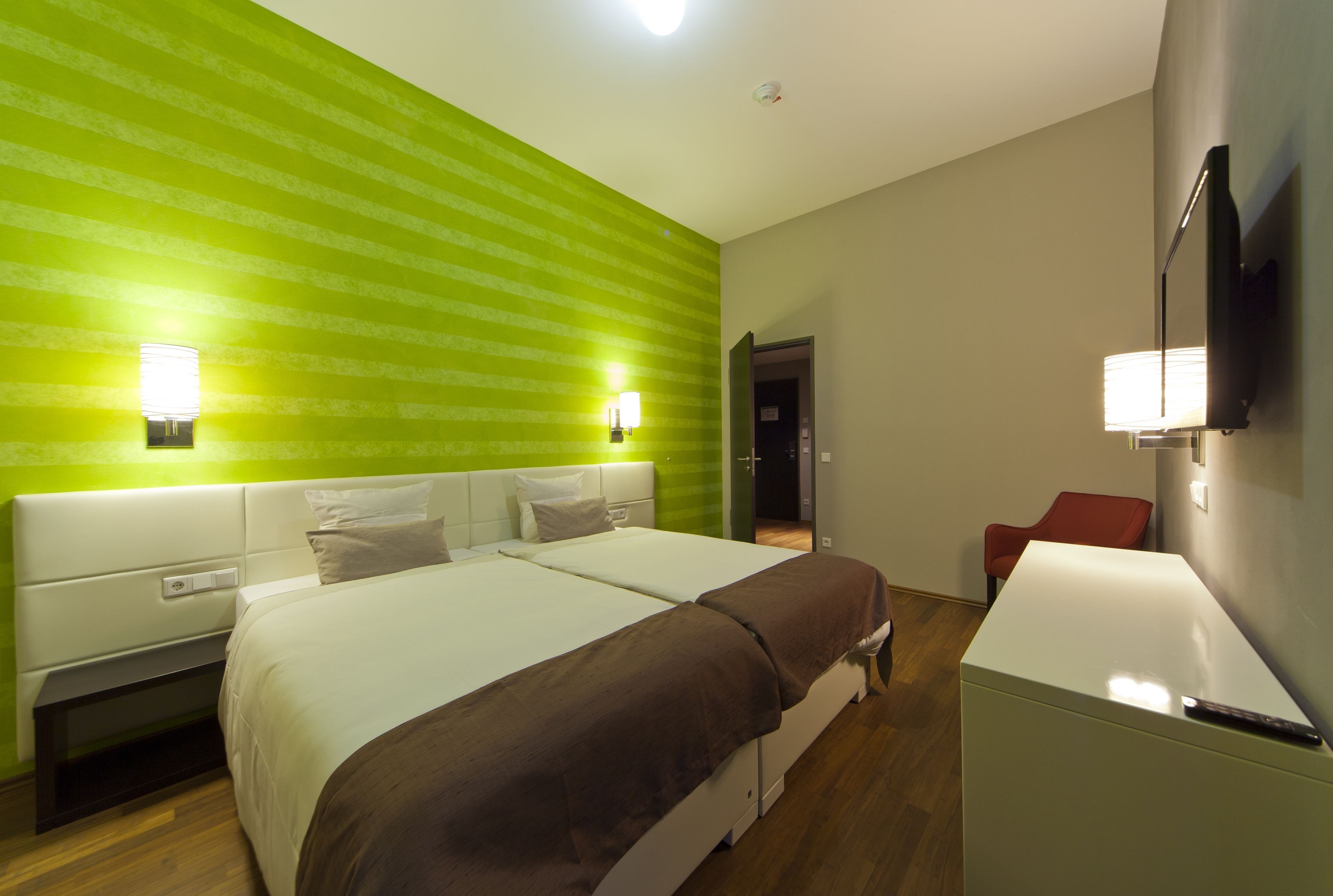 Habitación de hotel con dos camas, un escritorio, una silla y un televisor.