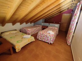 Una habitación con dos camas, techo de madera y pared roja.