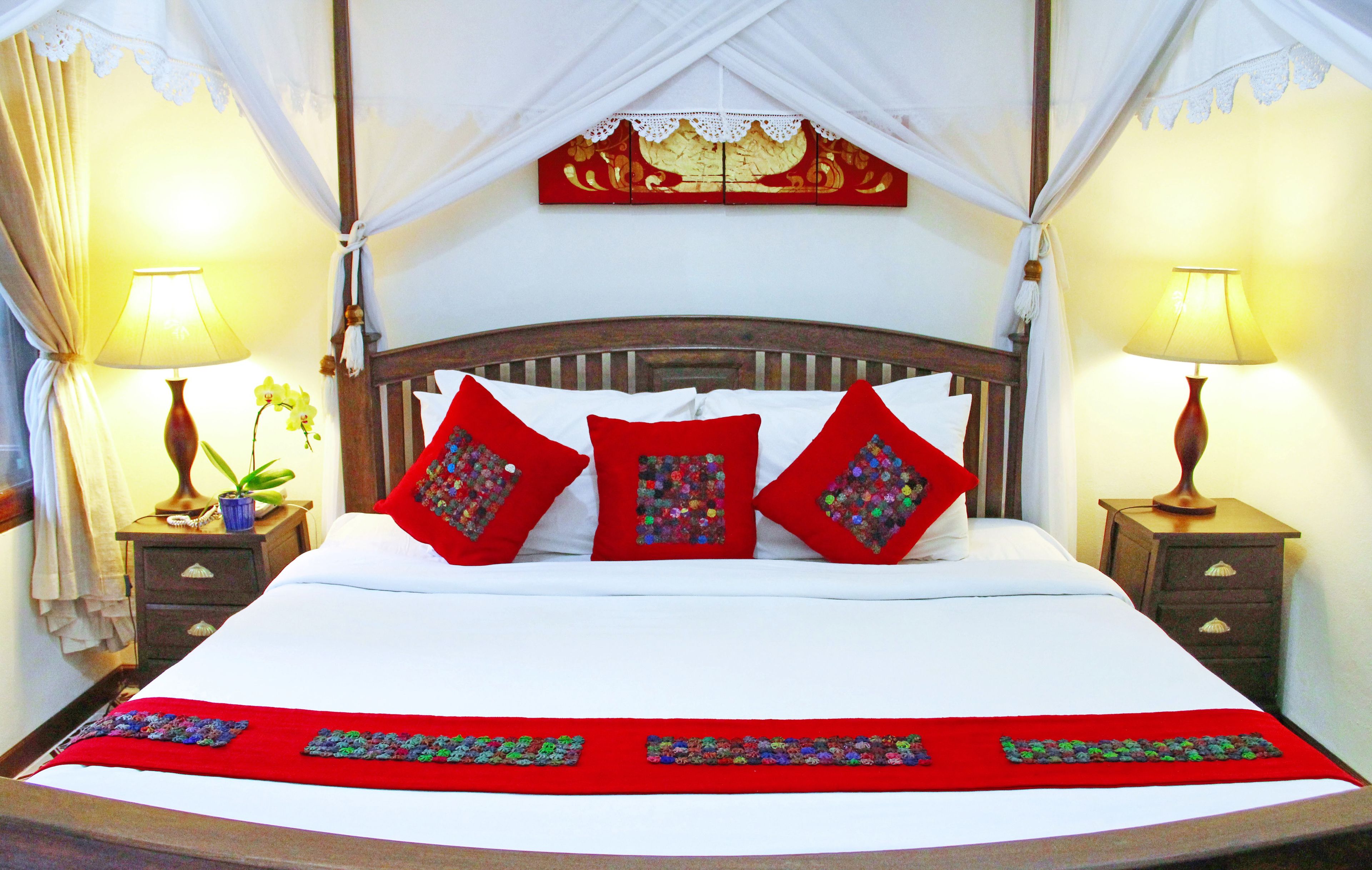 Una cama con dosel, almohadas y colcha rojas.
