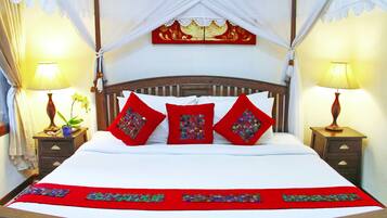 A bed with a canopy, red pillows, and a red bedspread.