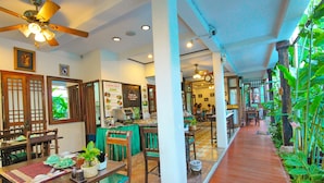Un restaurante tradicional con mobiliario de madera, suelo de baldosas y una pared cubierta de plantas verdes.