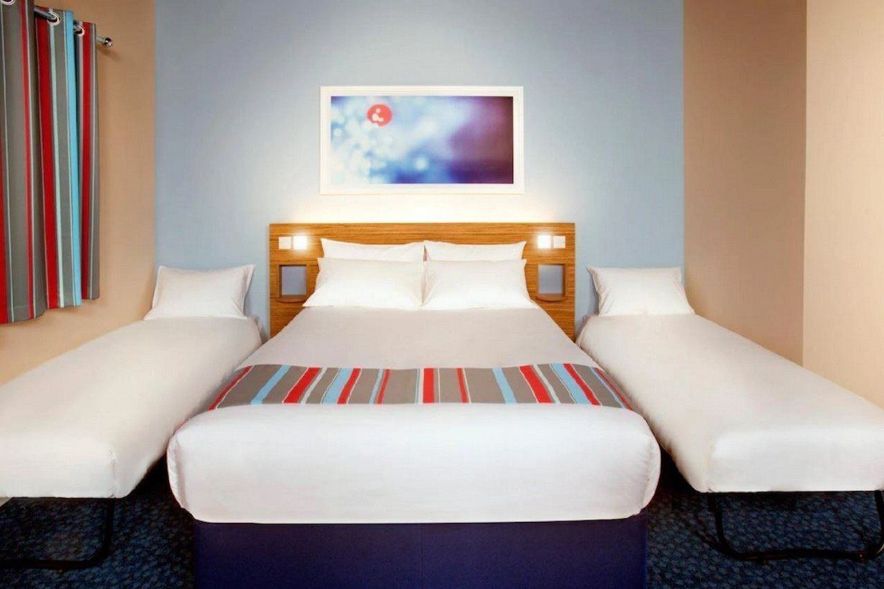 Une chambre d’hôtel avec un lit, deux tables de chevet, une tête de lit et un tableau au mur.