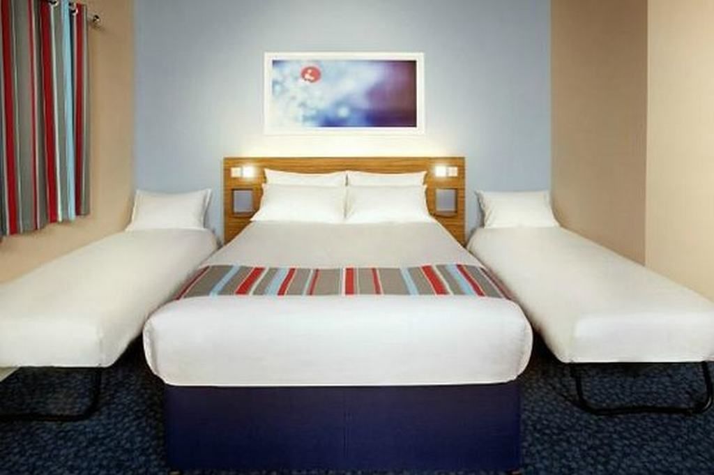 Ein Hotelzimmer mit einem Einzelbett, zwei Nachttischen und einem an der Wand hängenden Kunstwerk.