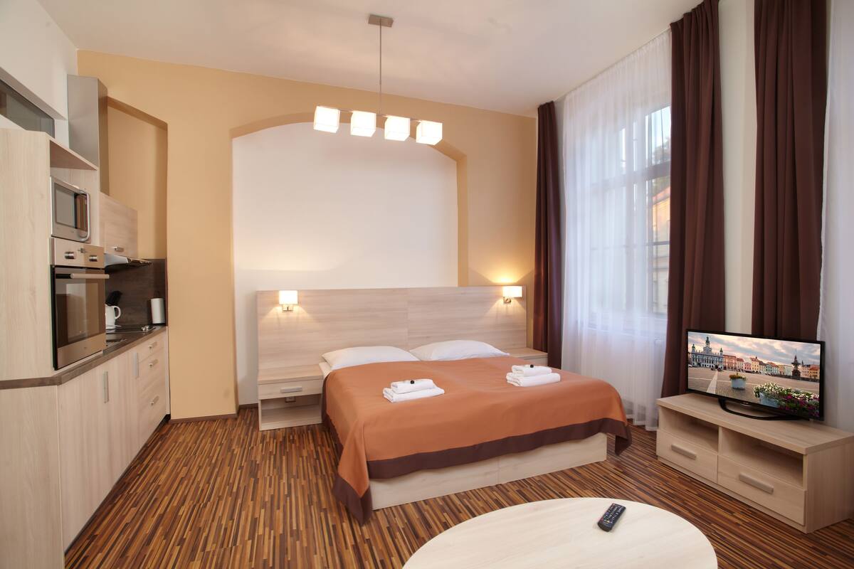 Una habitación de hotel con cama, televisión, escritorio y kitchenette.