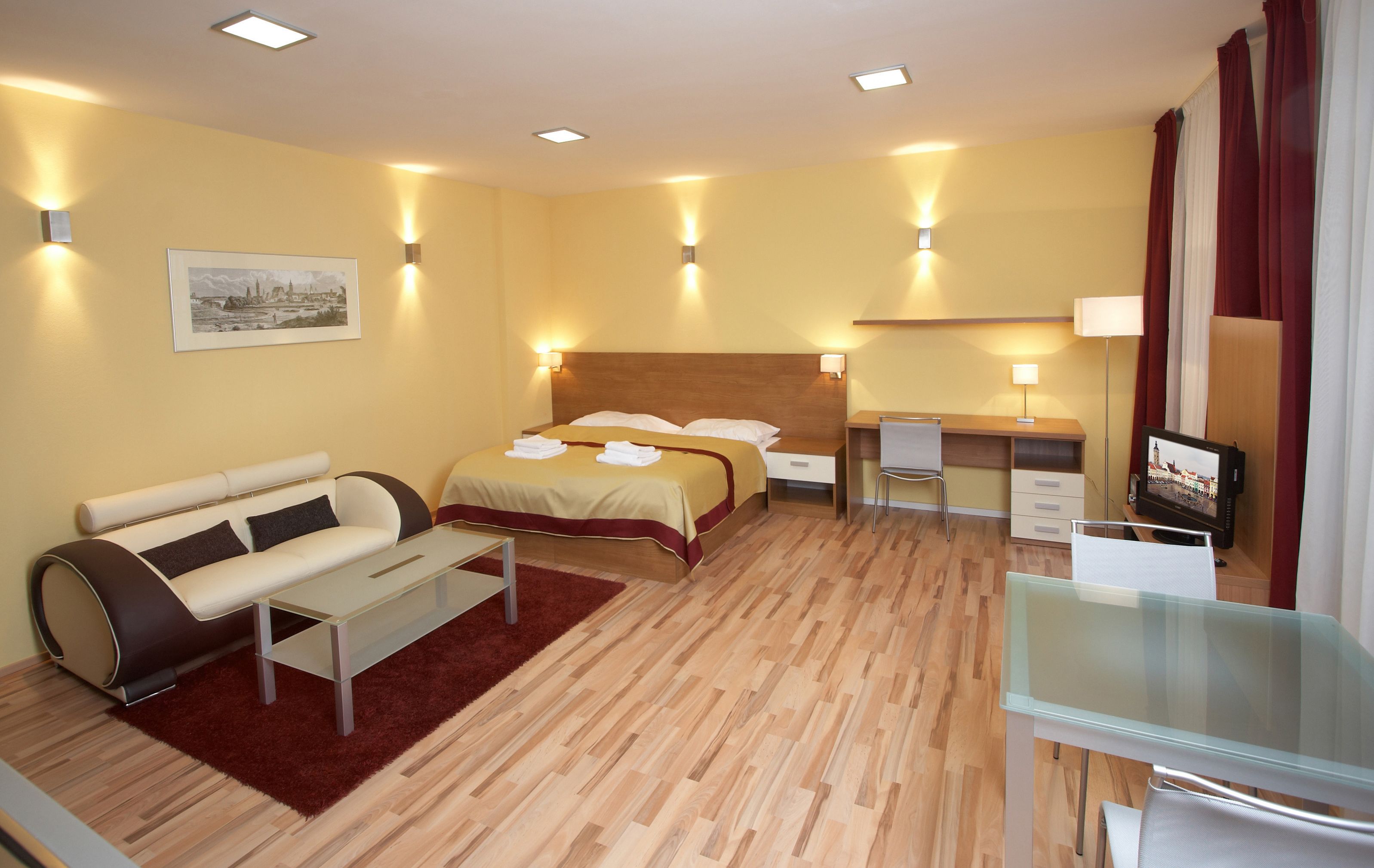 Ein Hotelzimmer mit einem Bett, einem Sofa, einem Schreibtisch und einem Fernseher.