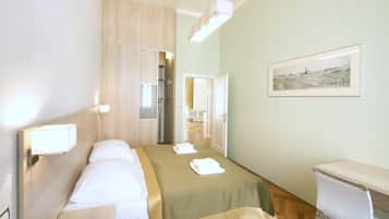 Una habitación de hotel con cama, mesita de noche, escritorio y un cuadro en la pared.