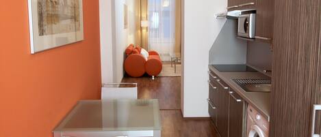 A compact kitchen with a dining area, a washing machine, and a framed picture on the wall.