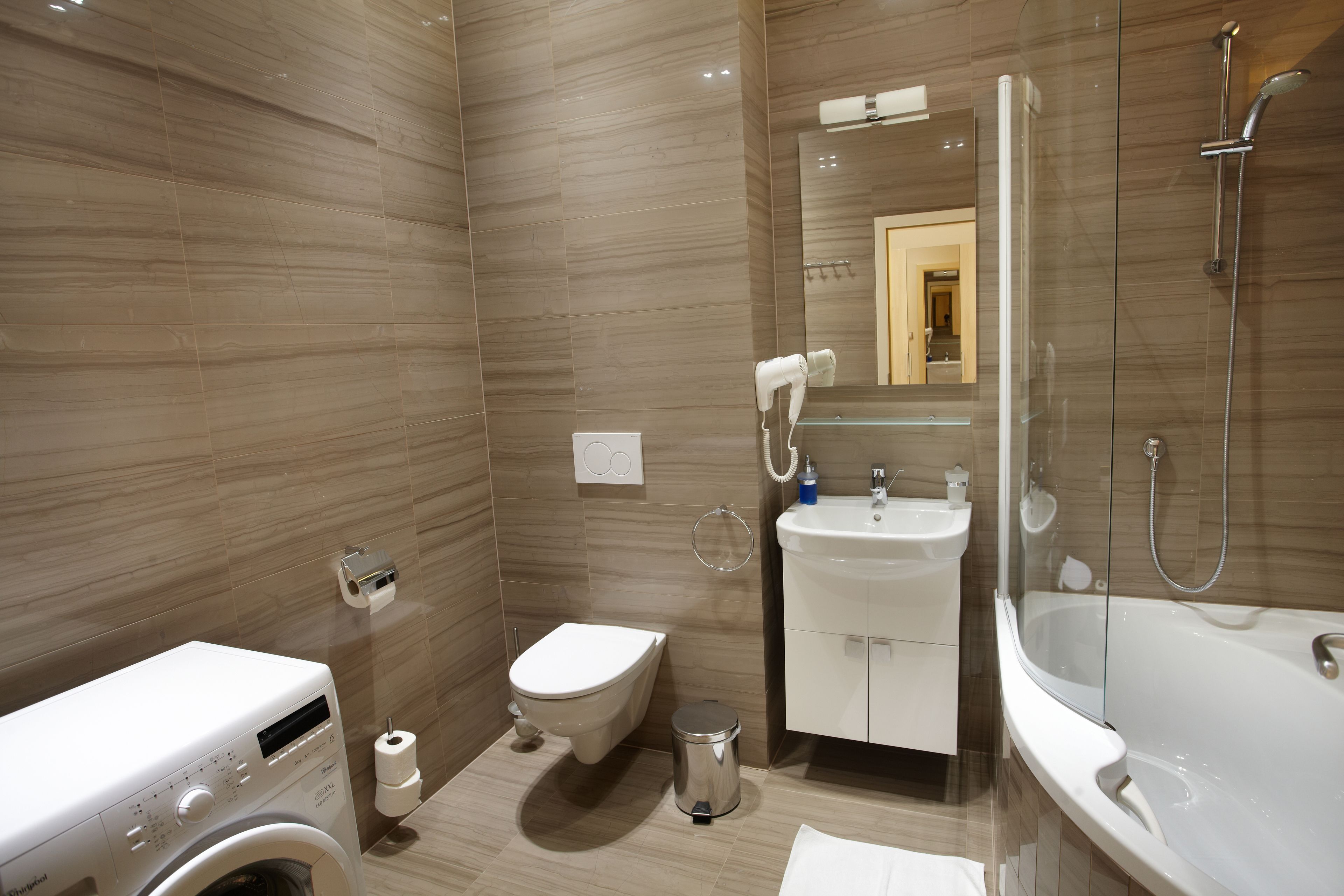 Un baño moderno con lavadora, inodoro, lavabo y bañera.